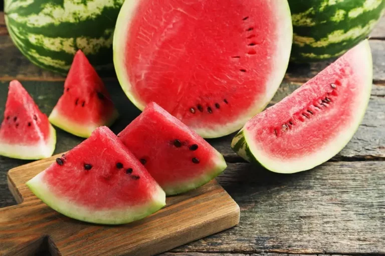 Sliced watermelon on a wooden cutting board with heirloom crimson sweet watermelon seeds.